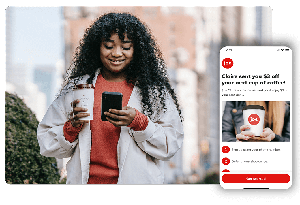 Woman holding hot coffee to-go and looking at phone that displays a joe promotion